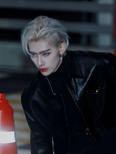 a woman with white hair and black leather jacket next to a fire hydrant wearing red lipstick