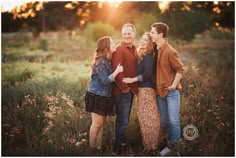 three people standing together in a field at sunset