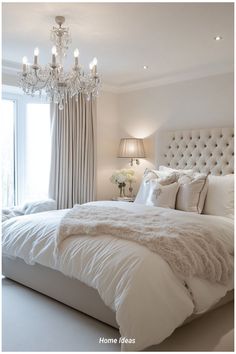 a bedroom with a chandelier and white bedding