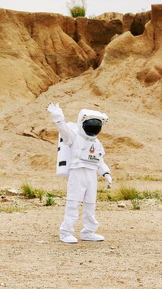 an astronaut standing in the desert waving