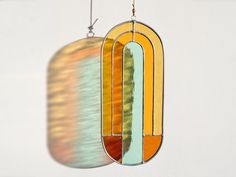 a stained glass sun catcher hanging from a hook on a wall in front of a white wall