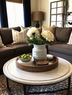 a living room filled with furniture and flowers in a vase on top of a coffee table