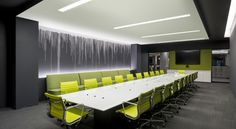 an empty conference room with green chairs and white table in front of a waterfall on the wall