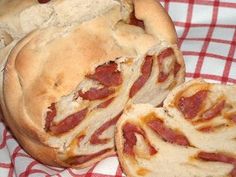 two pieces of bread with bacon inside on a red and white checkered table cloth