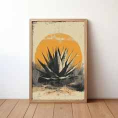 an art print of a large cactus in front of the sun on a wood floor