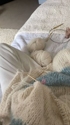 a person laying on a bed with some yarn