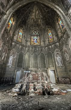 the interior of an abandoned church with stained glass windows and crumbling stairs in front of it