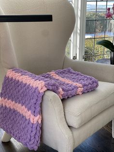 a white chair with a purple and pink blanket on it