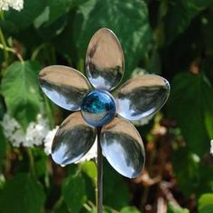 a close up of a metal flower on a plant with white flowers in the background