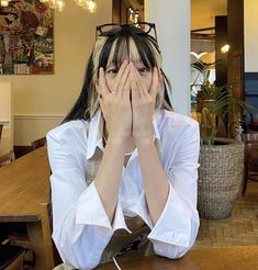 a woman sitting at a table covering her face