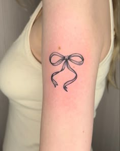 a woman's arm with a bow tattoo on the left side of her arm