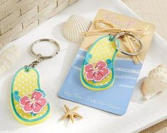 two keychains with flowers on them sitting next to shells and seashells