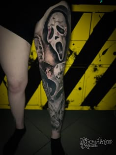 a person with a tattoo on their leg is standing in front of a yellow and black striped wall