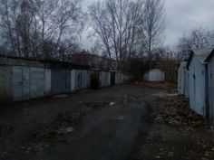 an old run down building with lots of doors on the front and back walls, next to a dirt road