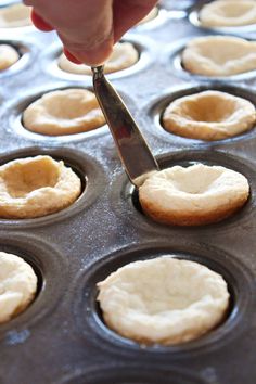 a person is using a knife to cut some food in the muffin tins