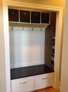 an empty room with white cabinets and black drawers on the wall, along with wooden flooring