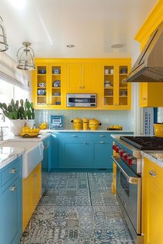 a kitchen with yellow and blue cabinetry, white counter tops, and tile flooring