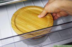 a person holding a wooden plate in front of an oven