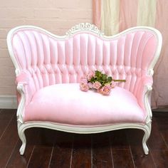 a pink couch sitting on top of a hard wood floor