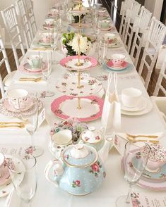 a long table is set with tea cups and saucers, plates and napkins