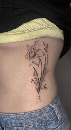 a woman's stomach with a flower tattoo on her lower side ribcage