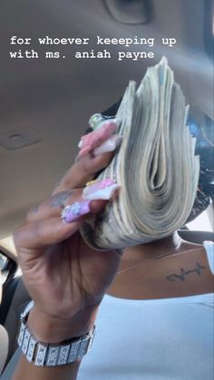 a woman holding up a stack of money in the back seat of a car with her hand on top of it