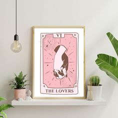 the lovers tarot card art print displayed on a shelf next to potted plants