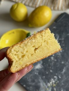 a person holding a piece of cake in front of lemons and a cutting board