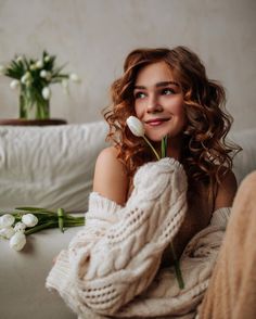 a woman sitting on a couch with flowers in her hand