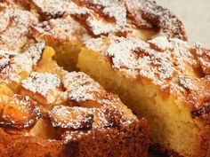 a cake with powdered sugar on top is cut into pieces and sits on a plate