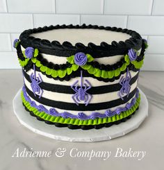 a multi layer cake decorated with black, green and purple icing on a white plate