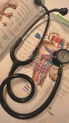 a stethoscope sitting on top of an open book with medical diagrams in the background