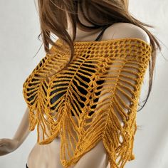 a mannequin wearing a yellow crochet shawl on top of a white background