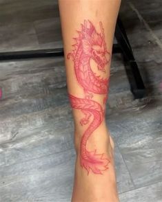 a woman's foot with a red dragon tattoo on her left leg and pink flowers in the background