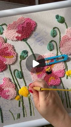 someone is painting flowers on a canvas with crochet