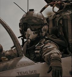 a man sitting in the cockpit of a fighter jet with his hand on the pilot's shoulder