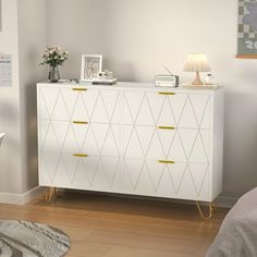 a white dresser with gold handles in a bedroom