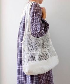 a woman is holding a white bag in her hands and looking at the wall behind her