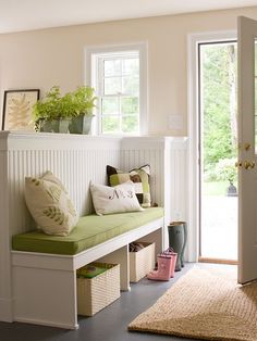 a white bench with green cushions in front of a door