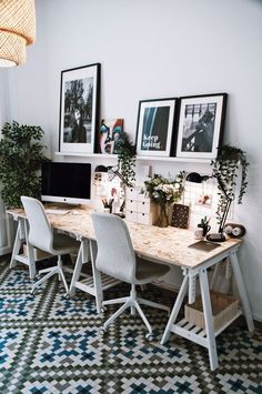 a table with four chairs and pictures on the wall above it in a home office