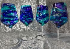 three wine glasses with blue and green designs on the rims, one is empty