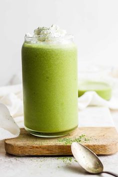 a green smoothie in a glass with whipped cream and sprinkles on top