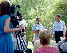 a group of people standing around each other in front of a camera man and woman