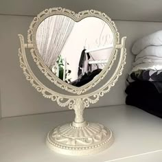 a mirror that is on top of a white shelf with clothes in the back ground