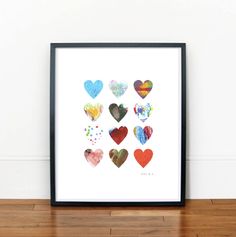 an art print with hearts painted on it in various colors and sizes, sitting on a wooden floor