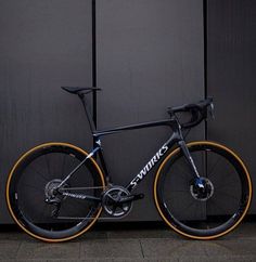 a black and orange bike parked in front of a gray wall with the word genius written on it