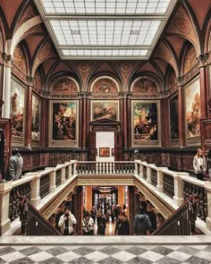 people are walking up and down the stairs in an ornate building with paintings on the walls