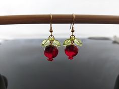 This image features a beautiful jewelry set inspired by pomegranates, crafted from resin with stainless steel components. The set includes earrings and a matching necklace, each designed with a deep red resin pomegranate as the focal point. The pomegranates are detailed with small green leaves, also made from resin, giving them a lifelike appearance. The earrings hang elegantly from gold-toned stainless steel hooks, while the necklace features a delicate gold-toned chain. The vibrant red of the pomegranate contrasts beautifully with the golden chain and hooks, creating a striking and elegant piece that would be perfect for adding a touch of nature-inspired charm to any outfit. This jewelry set is durable due to the stainless steel parts, making it a lasting addition to your collection. The Resin Pomegranate, Golden Chain, Resin Charms, Threader Earrings, Matching Necklaces, Steel Jewelry, Stainless Steel Jewelry, Hook Earrings, Vibrant Red