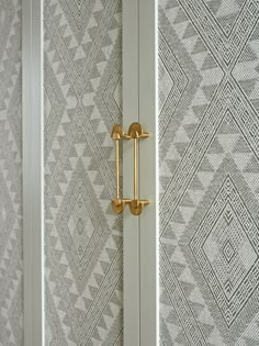 the door handles are gold and silver in this room with geometric wallpaper on the walls