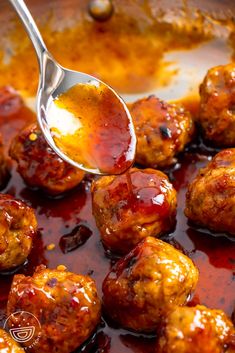 the meatballs are covered in sauce and being spooned with a ladle to stir them